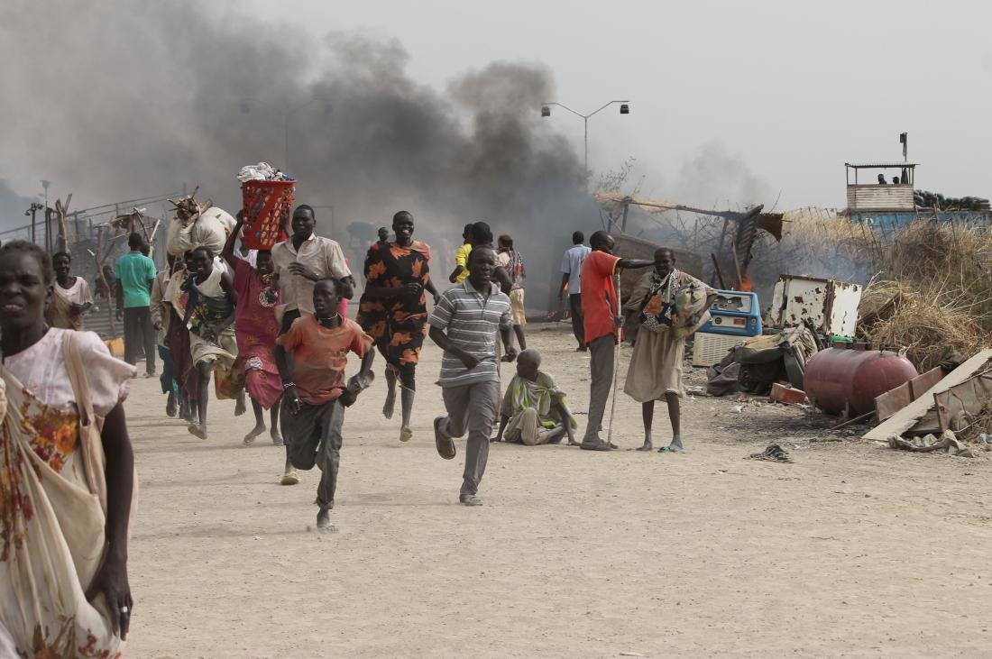 TOPSHOT - South Sudanese civilians flee fighting in an United Nations base in the northeastern town of Malakal on February 18, 2016, where gunmen opened fire on civilians sheltering inside killing at least five people. Gunfire broke out in the base in Malakal in the northeast Upper Nile region on February 17, 2016 night, with clashes continuing on Thursday morning that left large plumes of smoke rising from burning tents in the camp which houses over 47,000 civilians.  / AFP / Justin LYNCH        (Photo credit should read JUSTIN LYNCH/AFP/Getty Images)