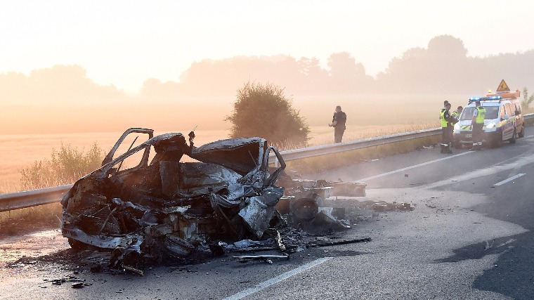 Calais, 2017. június 20. Kiégett autóroncs körül rendőrök és tűzoltók 2017. június 20-án, miután egy autó vezetője migránsok által faágakból épített útakadály miatt veszteglő kamionba rohant az A16-os autópályán, Calais francia kikötőváros közelében. Az autós életét vesztette. (MTI/EPA/Guy Drollet)
